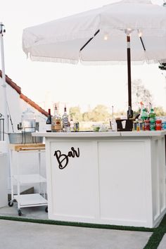 a bar with an umbrella over it and bottles on the counter top next to it