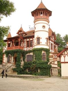 an old building with ivy growing on it's sides and a clock tower in the background