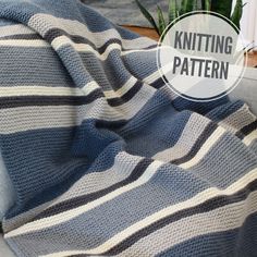 a blue and white striped blanket sitting on top of a couch next to a potted plant