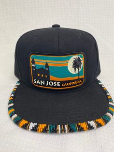 You are viewing a hand-beaded baseball hat with a Bart Bridge San Jose, California patch. The hat is ADULT size. All beads are sewn by hand.  All patches are applied by hand. No two hats are exactly alike and will never be replicated exactly. Made by an indigenous artist, I am an enrolled member of the Jumano Nation of West Texas. Free shipping to US locations only Casual Beaded Hats With Flat Brim, Casual Beaded Flat Brim Hat, Beaded Cap Hats For Festivals, Handmade Snapback Baseball Cap For Festival, Handmade Snapback Hat, Adjustable Snapback Hat With Patches And Curved Brim, Adjustable Snapback Hat With Patches And Flat Brim, Flat Bill Baseball Cap With Patches, Adjustable Flat Bill Baseball Cap With Patches