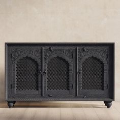 an ornate black cabinet with four doors on the front and side, against a beige wall