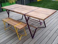 a table and bench on a deck with grass in the background