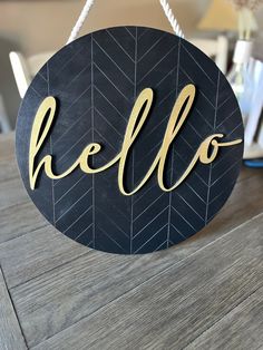 a wooden sign that says hello hanging from a string on top of a wood table