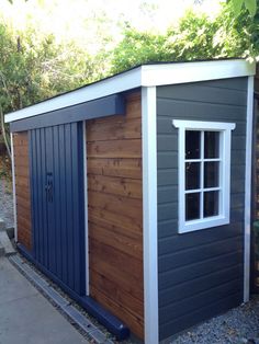 a small shed with windows and siding on the side