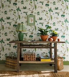 a table with two plants on it in front of a wallpapered background and basket