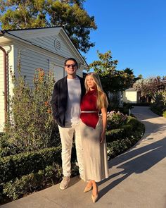 a man and woman standing in front of a house