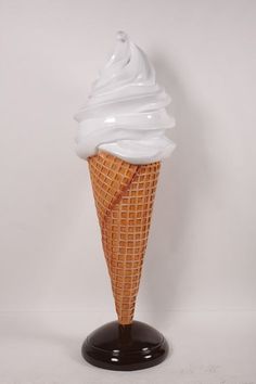 an ice cream cone with white icing in a black stand on a white background