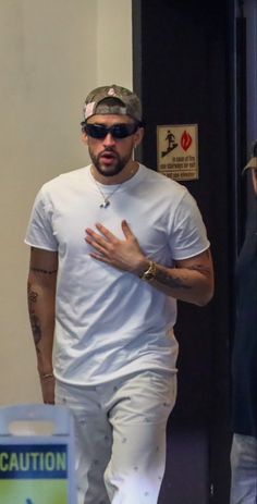 a man in white shirt and pants walking with his hand out to someone behind him