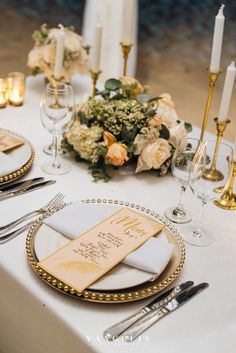 the table is set with white and gold place settings