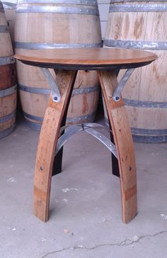 a table made out of wine barrels in a room filled with wood and metal casks