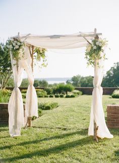 an outdoor wedding setup with white drapes and flowers