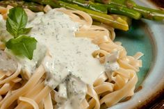 a plate with pasta, asparagus and sauce on it