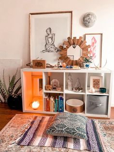 a living room with a rug, bookshelf and pictures on the wall above it