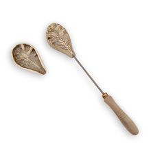 two metal objects with wooden handles on a white background, one is shaped like a leaf and the other has a wood handle