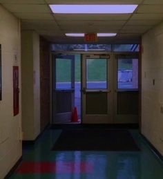 an empty hallway with two doors leading to another room and a red cone on the floor