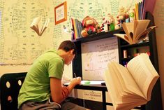 a young man sitting in front of an open book on top of a black desk