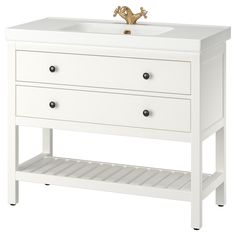 a white bathroom vanity with two drawers and a gold faucet on the sink