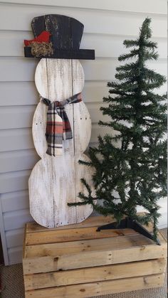 a wooden snowman next to a small christmas tree