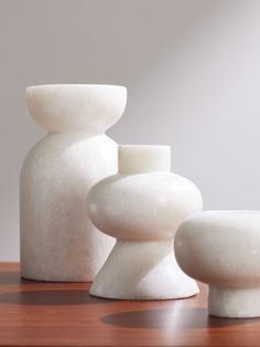 three white vases sitting on top of a wooden table