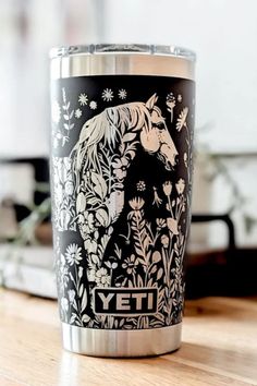 Black YETI tumbler with an intricate white floral design featuring a horse’s head among detailed wildflowers, placed on a wooden surface with a blurred background. Engraved Yeti Tumbler, Engraved Yeti, Yeti Tumbler, Embrace The Journey, Car Restoration, Beautiful Horse, Horse Drawings, Equestrian Life, Make Up Your Mind