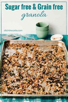 a baking pan filled with granola on top of a blue cloth next to a green cup