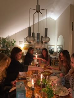 a group of people sitting around a table with food and candles in front of them