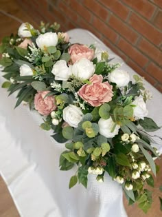 a bouquet of flowers sitting on top of a table next to a white cloth covered table