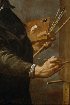 a man holding paintbrushes and an easel in his right hand