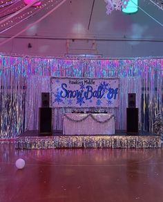 a stage set up for an event with balloons and streamers hanging from the ceiling