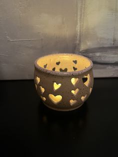 a ceramic bowl with hearts on it sitting on a black table next to a white wall