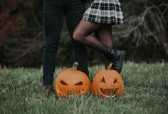 two people standing next to each other holding pumpkins