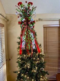 a decorated christmas tree with red, white and green bows on it's top