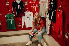 a woman sitting on the steps in front of lockers with soccer jerseys and balls