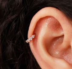 a woman's ear is shown with three small diamonds on the end of it