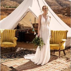 a woman standing in front of a white tent with yellow chairs and a green plant