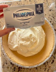 a person holding up a piece of cake with white frosting on it in a pie pan