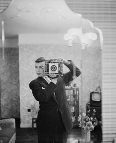 a man taking a selfie in front of a mirror with an old fashioned camera