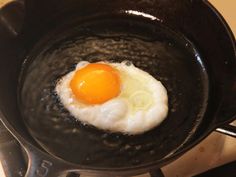 an egg frying in a skillet on top of a stove burner,