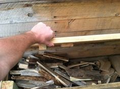 a man is reaching into a pile of wood