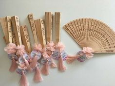 several wooden fans with pink tassels and tags attached to each one on a white surface