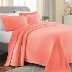 a bed with an orange comforter and pillows