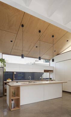 an open kitchen with white cabinets and wood ceilinging is shown in this modern home