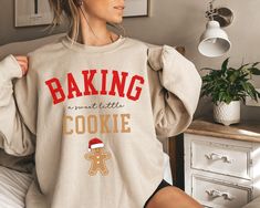 Are you looking for a trendy pregnancy Christmas sweatshirt for yourself or for someone you love? If that's the case, you're in the right place. This cute sweater, with a cute baking design, is meant to put a smile on your face every time you wear it and to help you deliver the great news of a baby on the way in a much jollier way. If you know someone who is pregnant and loves wearing Christmas themed clothes, this sweatshirt would make a great present for her.  Check out more pregnancy themed d Baking Design, Christmas Pregnancy Announcement, Christmas Pregnancy, Present For Her, Cute Baking, Pregnancy Reveal, Presents For Her, Baby On The Way, Maternity Sweater