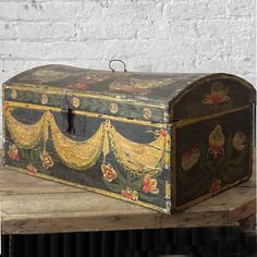 an old trunk sitting on top of a wooden table next to a white brick wall