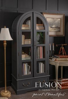 a room with a bookcase and lamp next to a table in front of it