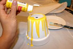 a person is painting a cake with yellow icing on the top and white frosting on the bottom