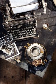 an old fashioned typewriter sitting on top of a wooden table next to other items