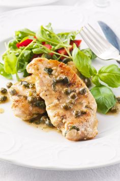 two pieces of meat with green vegetables on a white plate