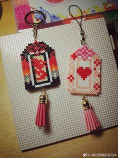 two earrings with tassels on top of a piece of paper next to each other