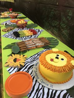 a table topped with cakes and desserts on top of green tables clothed in zebra print